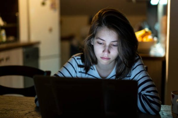 Young girl is crying lonely with tears in front of her laptop late at night